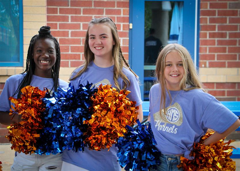 Three cheerleaders smile